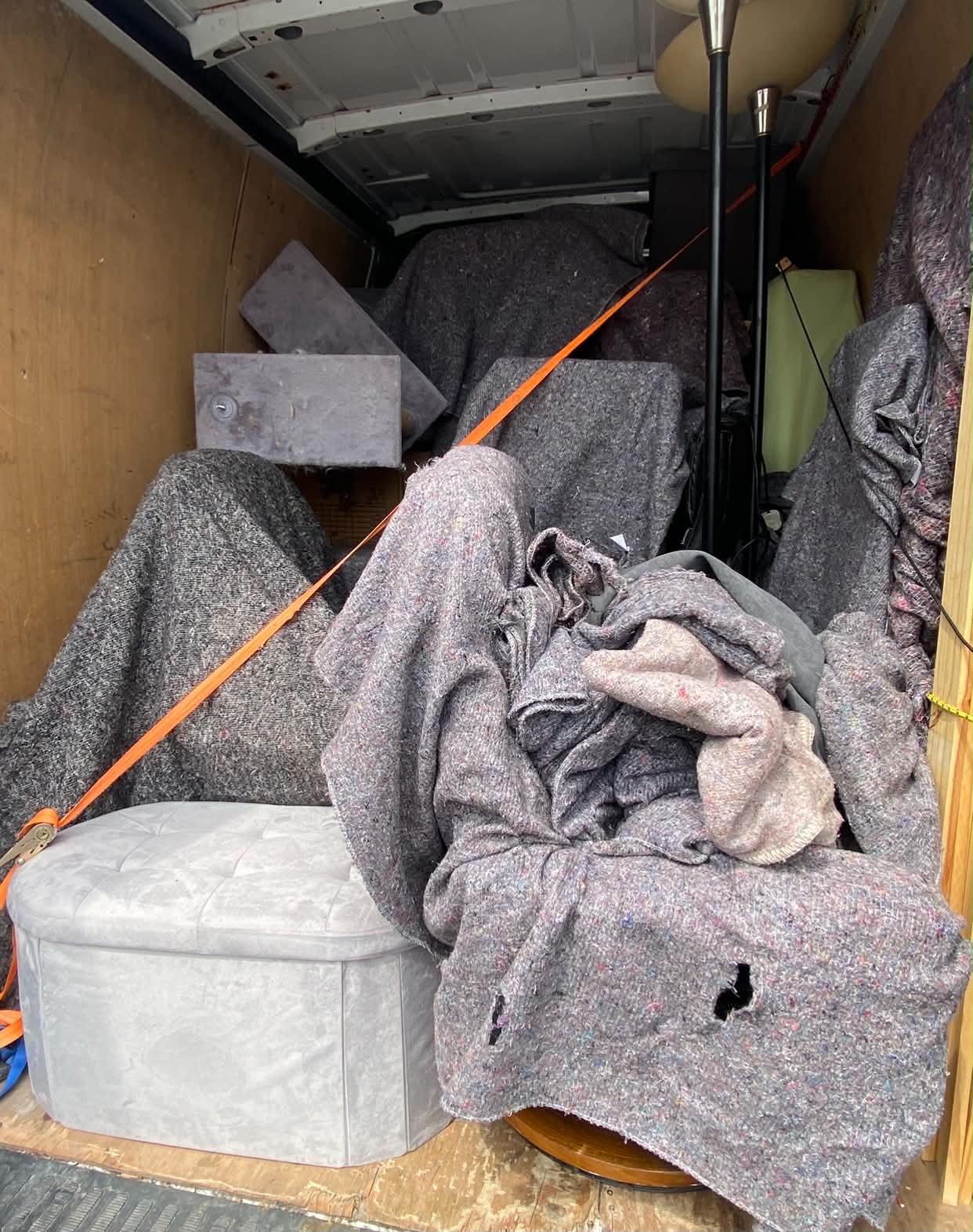 Furniture wrapped in protective blankets and strapped inside a removal van
